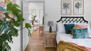Un dormitorio con cama, mesita de noche, lámpara y dos cuadros en la pared.