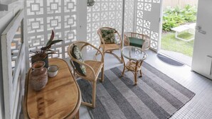 Una habitación con una mesa de comedor, sillas, una mesa de centro de vidrio, una alfombra estampada y vistas al exterior.