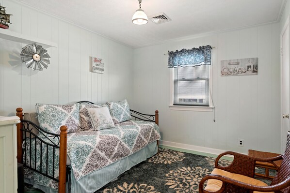 Un dormitorio con cama, ventana con persianas, un reloj de pared decorativo y una alfombra.