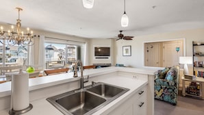 Een moderne keuken met een groot eiland, een roestvrijstalen spoelbak en een plafondventilator.