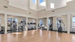 Een ruime fitnessruimte met meerdere loopbanden, elliptische trainers en een hometrainer.
