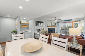 A modern living room with a dining area, a fireplace, and a view of the outdoors.