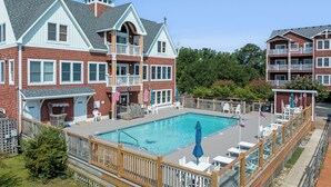 A large building with a swimming pool, multiple balconies, and outdoor seating areas. - North Bay Retreat: Waterfront, Shared Pool, Fitness Center, Short Stays Anytime (Manteo)