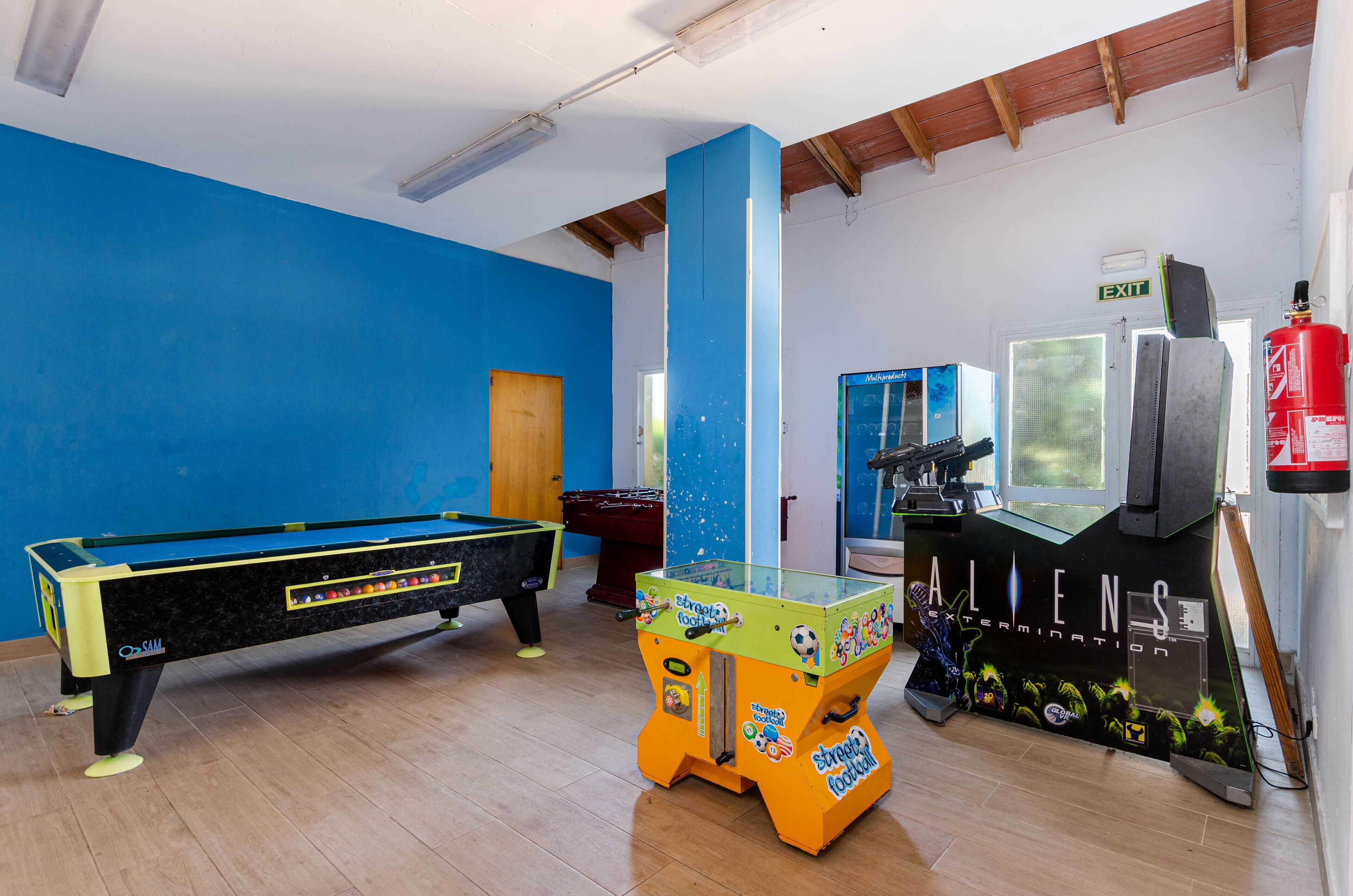 A room with a pool table, a foosball table, and a gaming console.