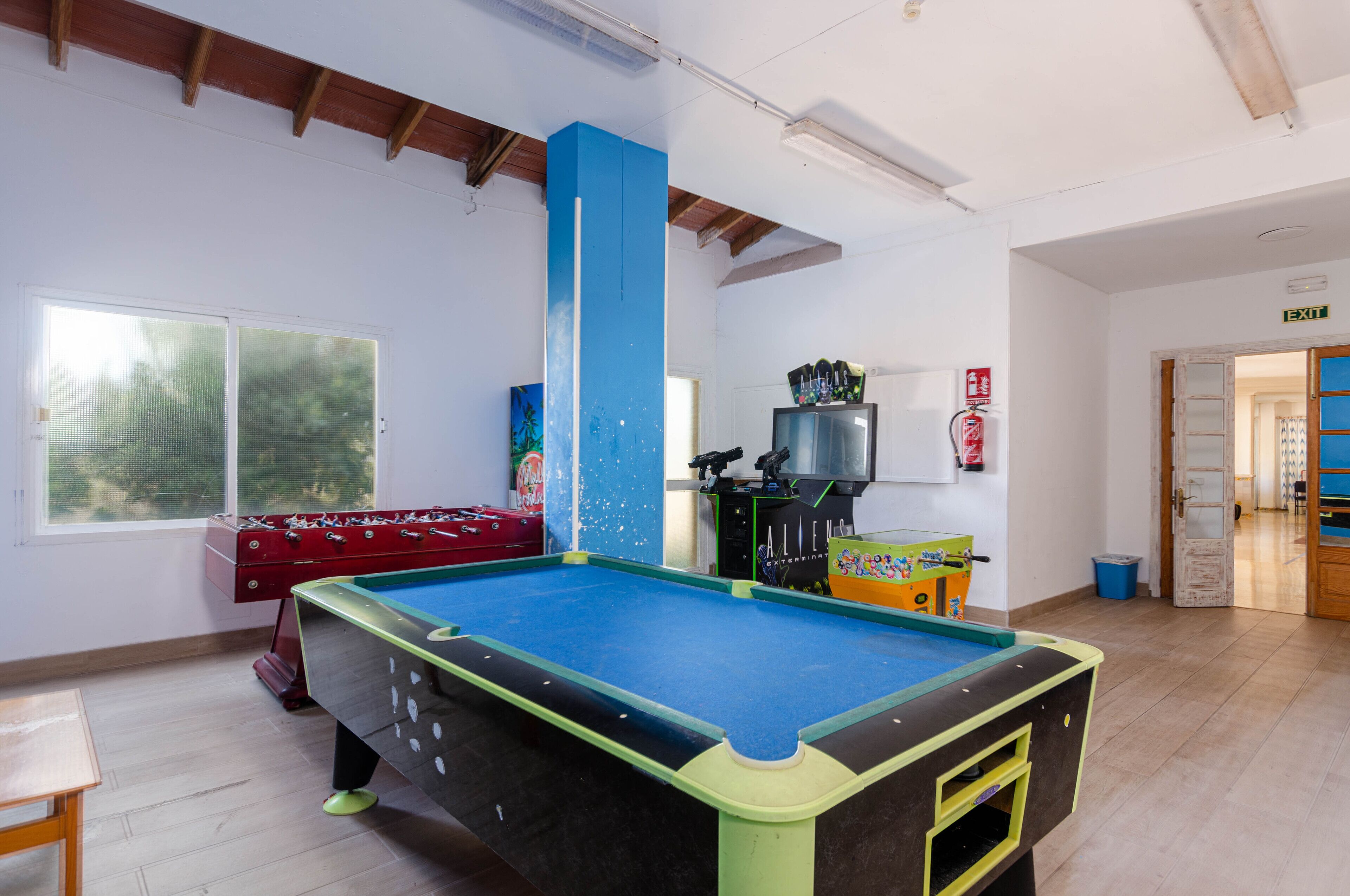 Una habitación con mesa de billar, mesa de futbolín y mesa de pool.