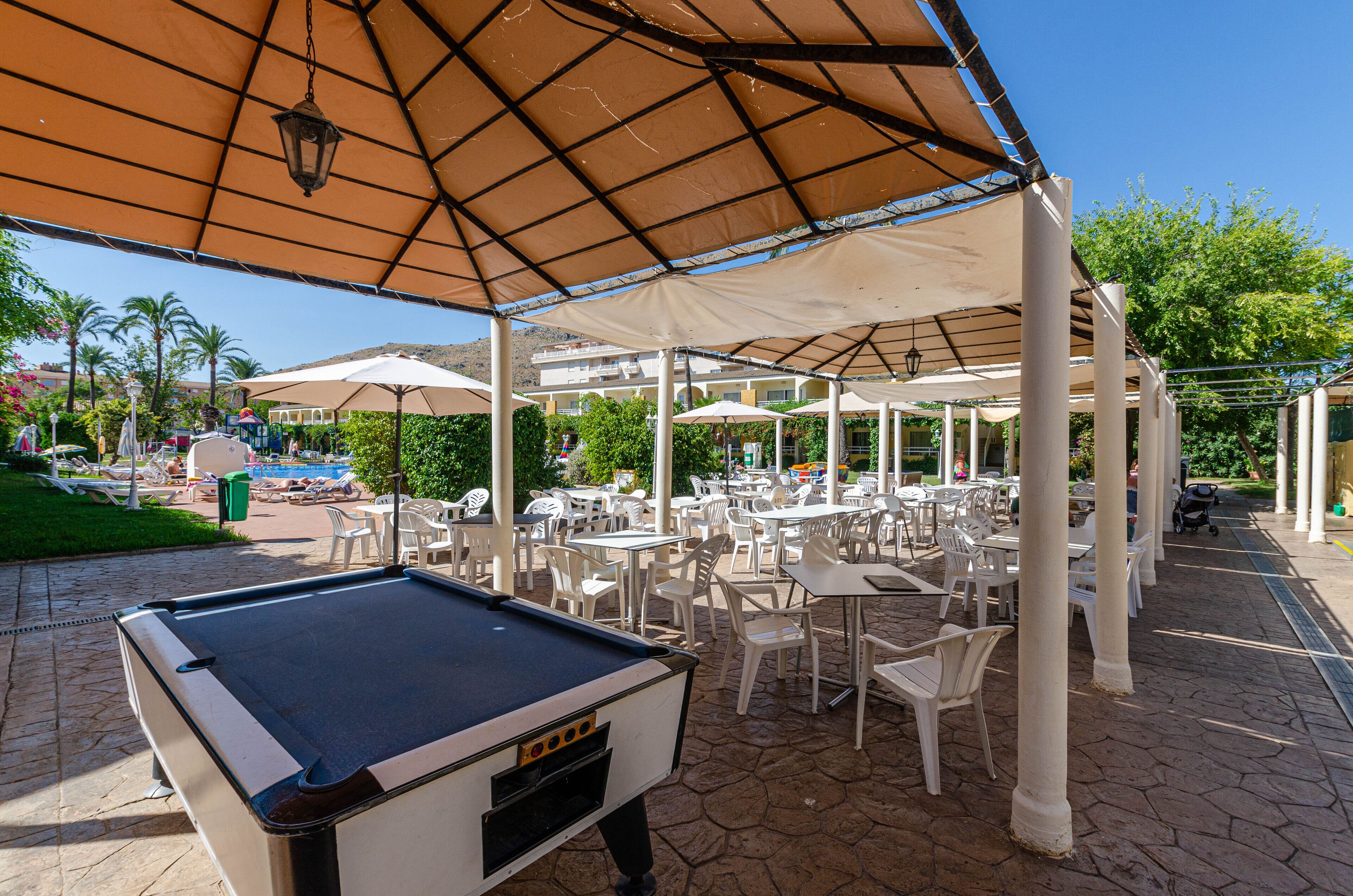 An outdoor patio area with pool tables, umbrellas, and seating arrangements.