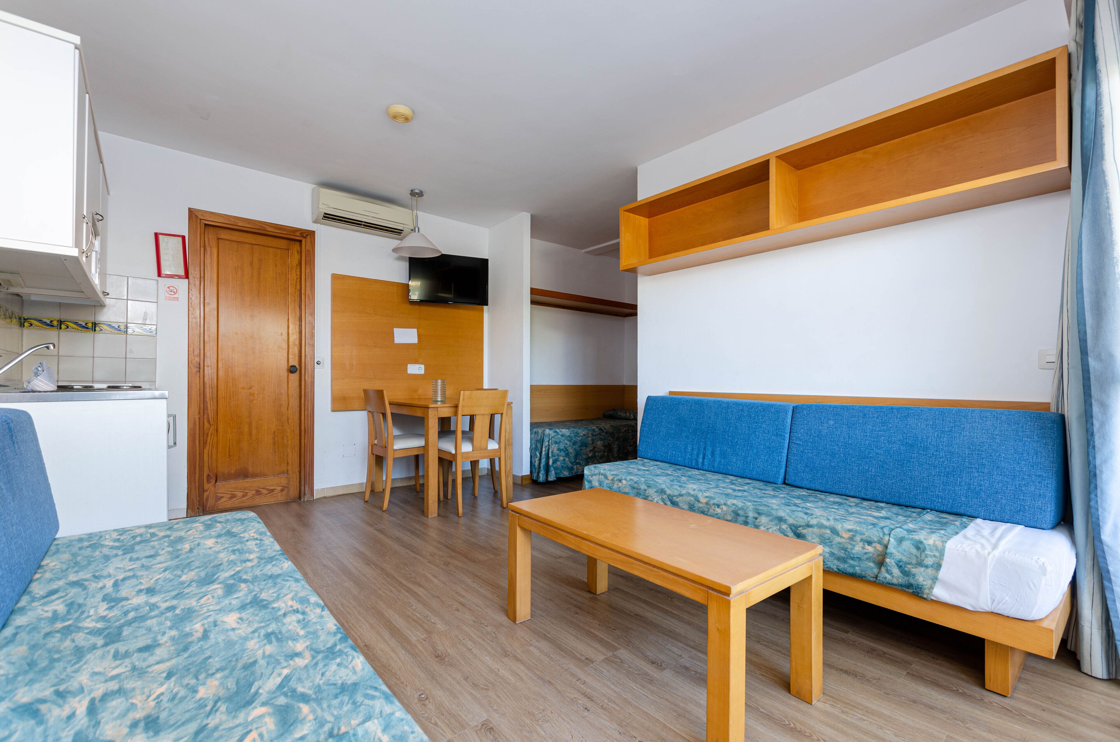 Ein kompaktes Zimmer mit Küchenzeile, einer Couch, einem Tisch und einem Stuhl.