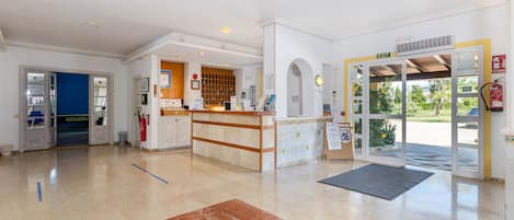 A hotel lobby with a reception desk, a blue door, and a large marble area.