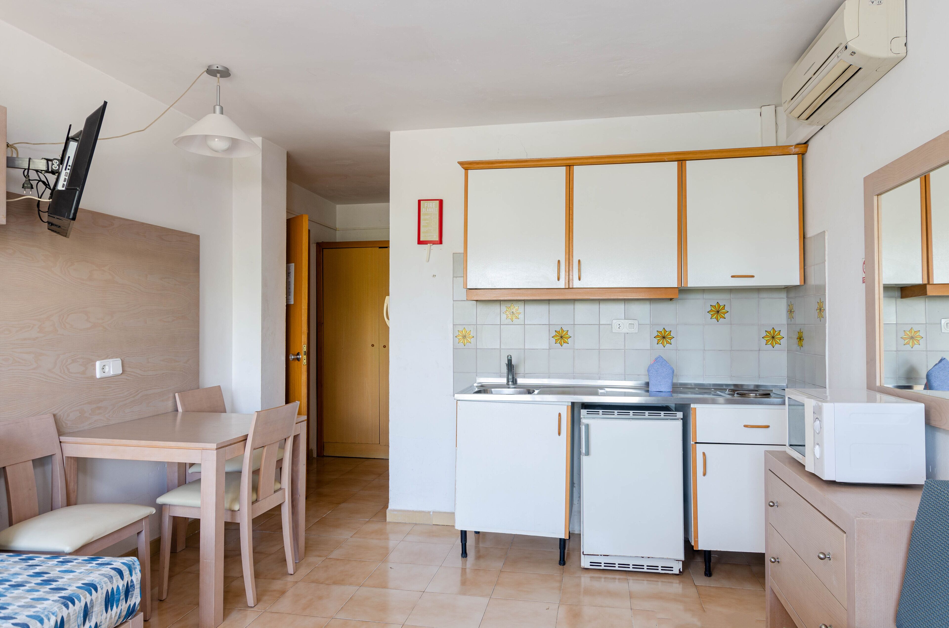 Una cocina compacta con armarios blancos, lavavajillas integrado y microondas en la encimera.