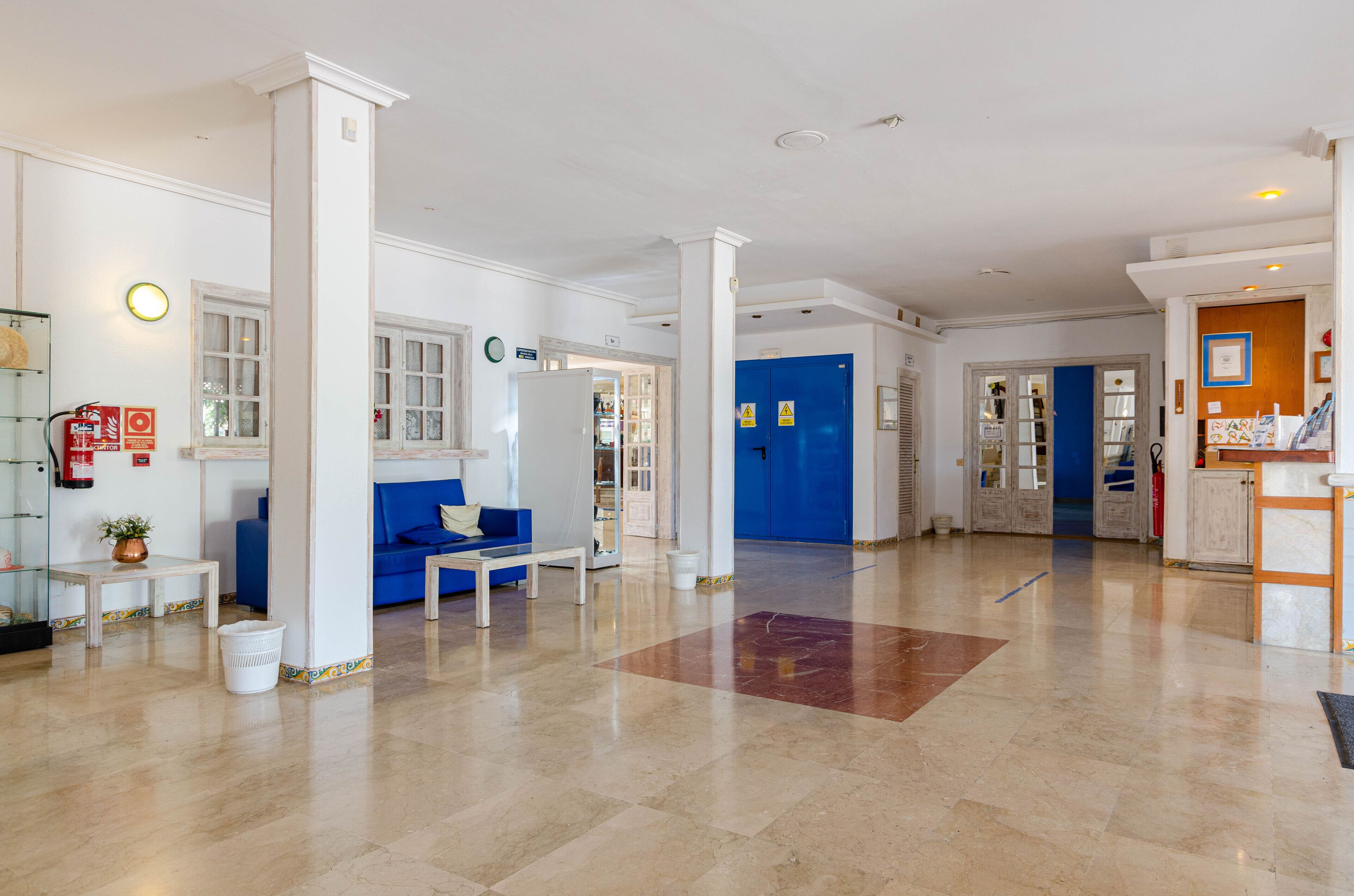 A spacious lobby with a blue sofa, white columns, and a marble floor.