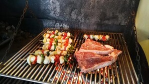 A grill with skewers of vegetables and two pieces of meat being cooked. - Mariner Club Apartments (Alcúdia)
