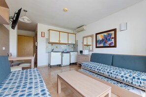 A compact living space with a kitchenette, a sofa, a dining table, and a bed. - Mariner Club Apartments (Alcúdia)