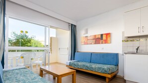 A modern living room with a sofa, a table, and a balcony with chairs. - Mariner Club Apartments (Alcúdia)