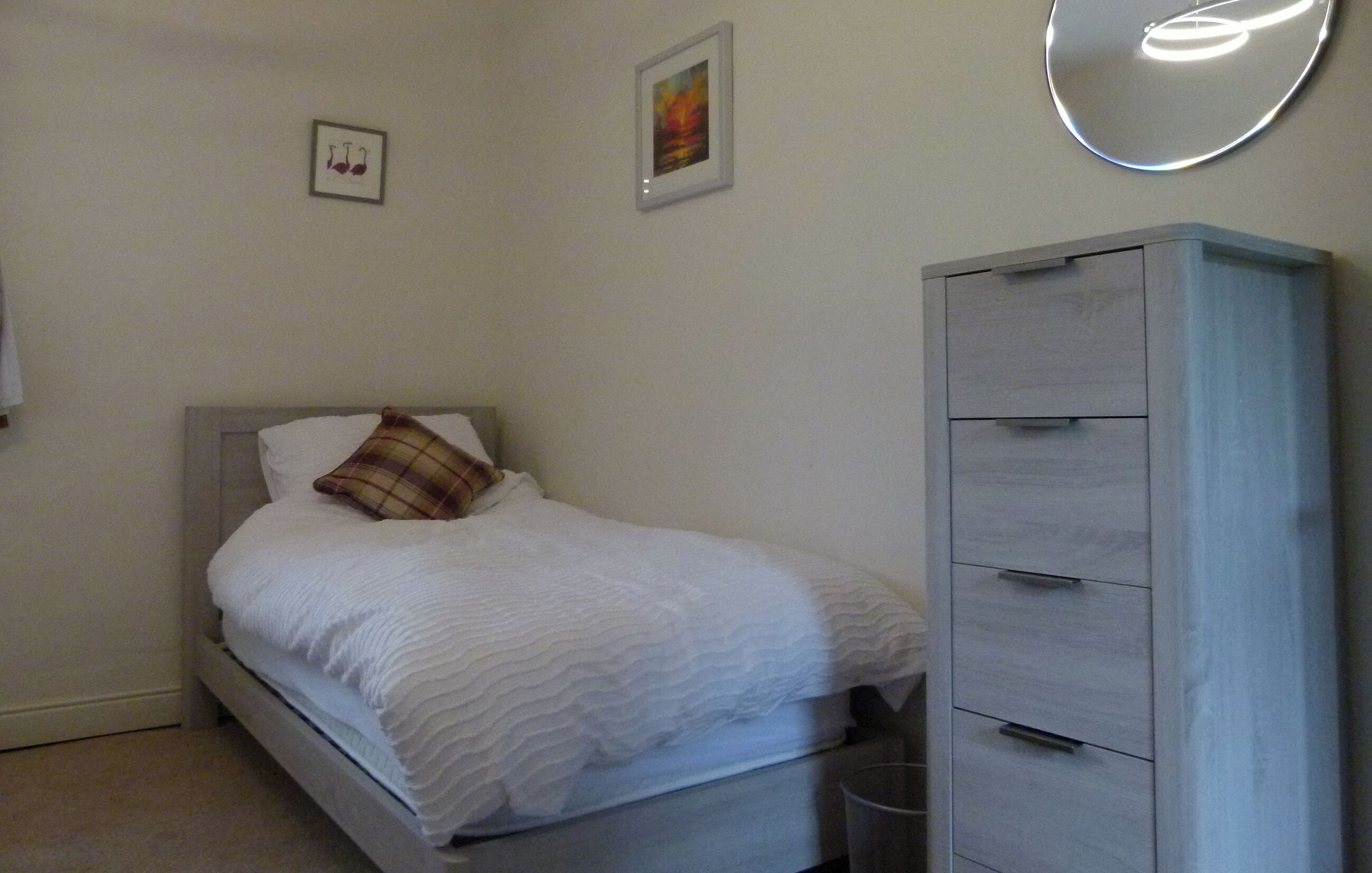 Ein Schlafzimmer mit einem Bett, einem Kleiderschrank und zwei gerahmten Bildern an der Wand.