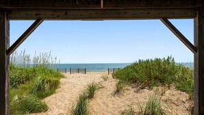 A beach view from a wooden structure with a sandy path leading to the water.