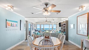 A dining area with a round table, white chairs, and a ceiling fan.