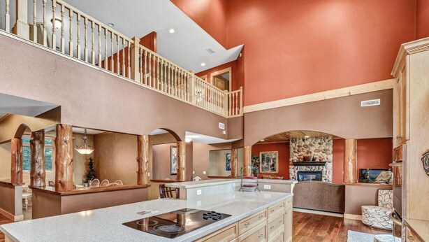 A spacious kitchen with a large island, wooden cabinets, and a stone fireplace.