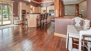 A spacious kitchen with wooden floors, a large island with bar stools, and a view of the outdoors.