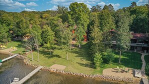 A lakeside view of a resort with a dock, grassy areas, and trees.
