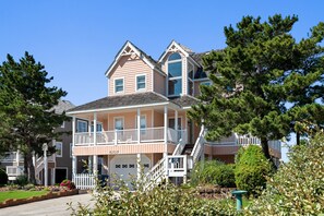 A two-story house with a garage, a balcony, and a staircase leading to the upper floor. - Tees & Tides: Soundside, Shared Pool & Tennis Court, Hot Tub, Golf Discounts (Nags Head)