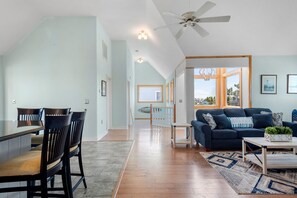 A spacious living area with a dining table, chairs, a sofa, and a ceiling fan. - Tees & Tides: Soundside, Shared Pool & Tennis Court, Hot Tub, Golf Discounts (Nags Head)