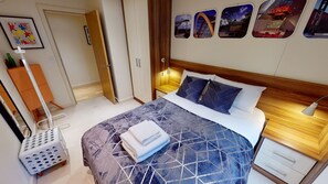 A hotel room with a neatly made bed, a wooden headboard, a bedside table with a lamp, and a wall with framed pictures. - Central Perks Apartment (Hull)