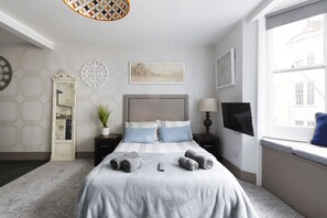 A neatly arranged bedroom with a bed, bedside tables, a TV, and a window with a view. - City Heart Brighton (Brighton)