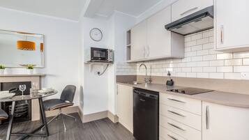 A compact kitchen with a microwave, dishwasher, and a small dining area with a table and chairs.