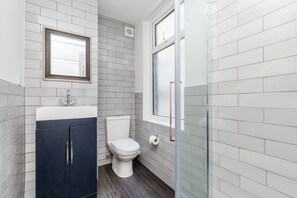 A bathroom with a toilet, a sink, and a mirror. - City Heart Brighton (Brighton)