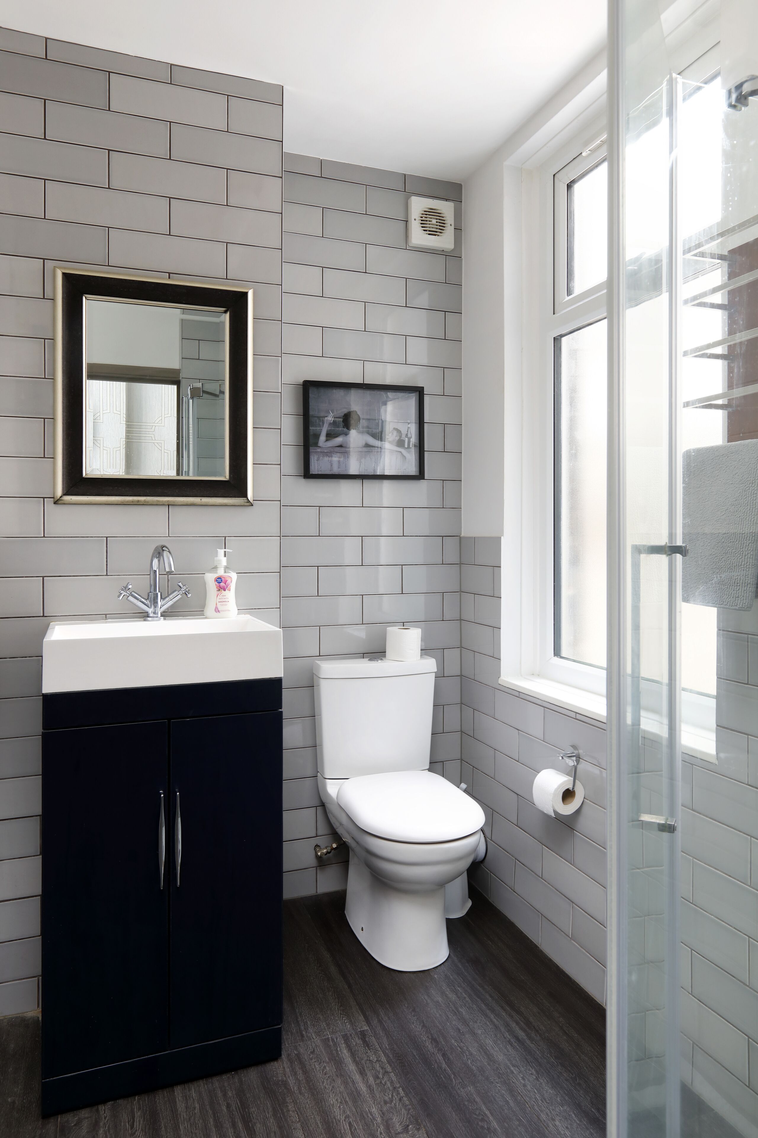 A bathroom with a white sink, a toilet, a mirror, and a shower.