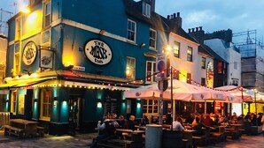 An outdoor seating area of a pub with tables and chairs, a sign reading "The Mash Tavern", and a "Restricted Zone" sign. - City Heart Brighton (Brighton)