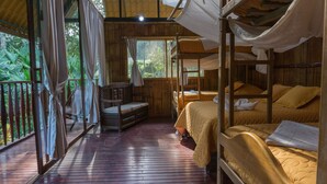 Una cabaña de madera con literas, un banco de madera y un balcón con cortinas.