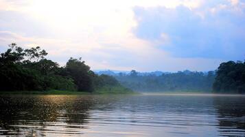 A calm river with reflections of trees and a misty horizon.