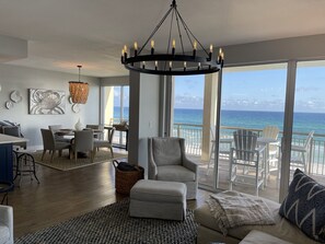 Relax in this stylish living area with a sofa, armchair, and dining table for four, offering a view of the ocean from the balcony.