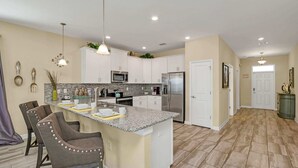 A modern kitchen with white cabinets, granite countertops, and stainless steel appliances. - Stunning and Spacious Home Near Disney, CDC Standards #rcg8521 (Davenport)