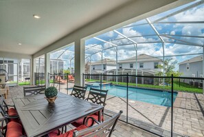 A covered patio with a pool, outdoor seating, and a view of neighboring houses. - Stunning and Spacious Home Near Disney, CDC Standards #rcg8521 (Davenport)