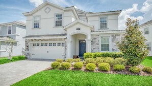 A two-story house with a garage, a front door, and a well-maintained lawn with various shrubs. - Stunning and Spacious Home Near Disney, CDC Standards #rcg8521 (Davenport)