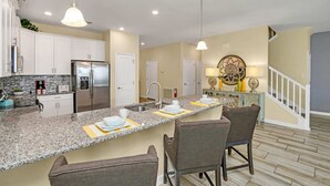 A modern kitchen with granite countertops, white cabinets, stainless steel appliances, and a central island with bar seating. - Stunning and Spacious Home Near Disney, CDC Standards #rcg8521 (Davenport)