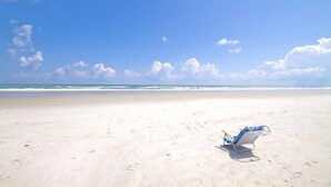A beach with a single beach chair and a clear sky. - Windjammer 210, 2 Bedrooms, Ocean Front, Pool, Elevator, Sleeps 6 (St. Augustine)