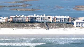 A coastal hotel with multiple buildings, a sandy beach, and a rocky shoreline.