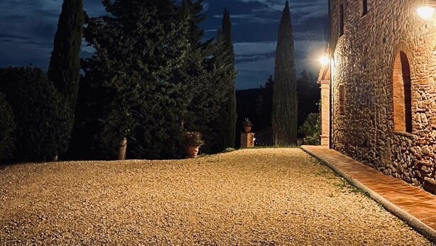Un bâtiment en pierre avec une allée gravillonnée et une pelouse bien entretenue.