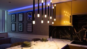 A modern kitchen with pendant lighting, marble countertops, and framed artwork on the wall. - The Opulence (Bradford)