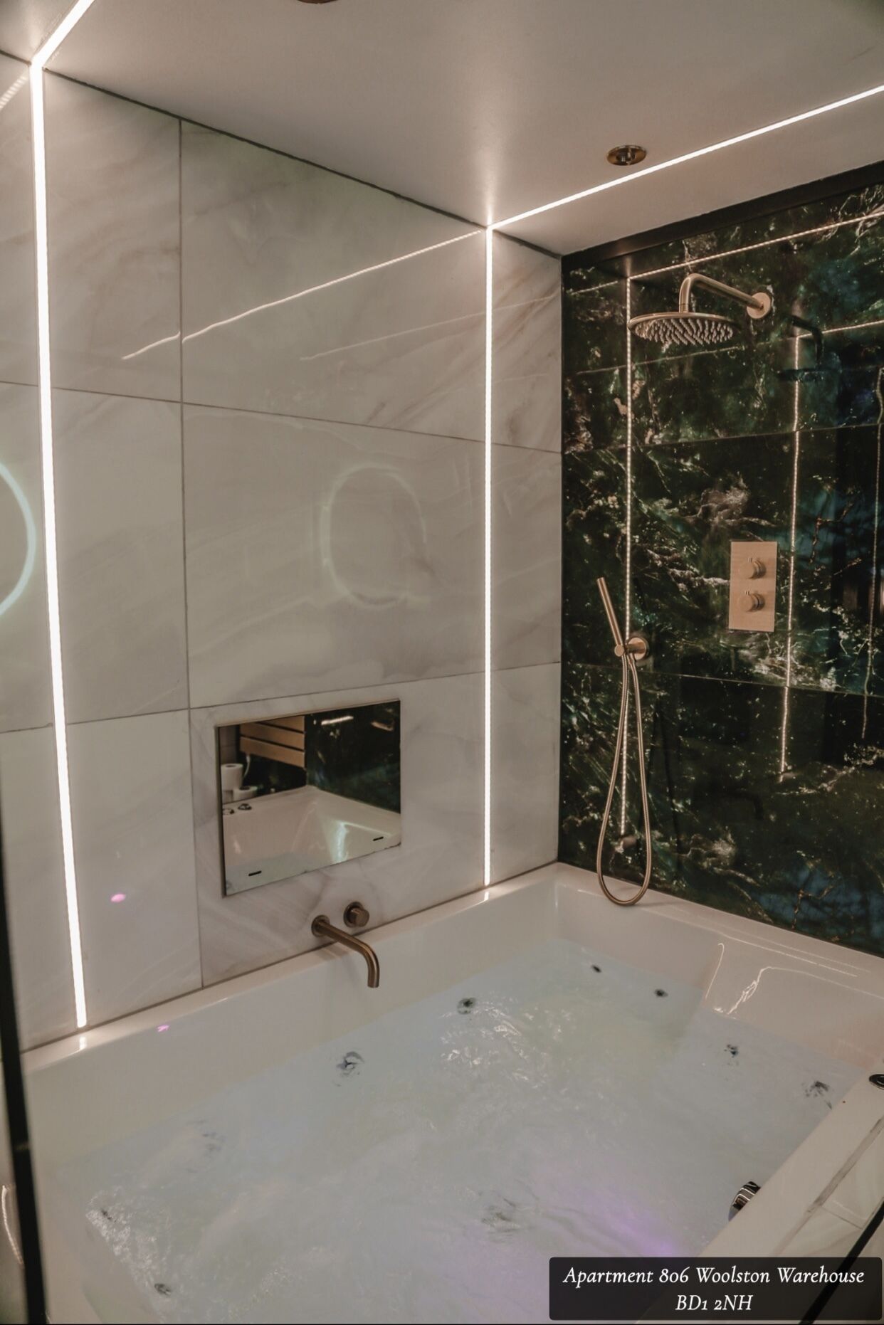 A modern bathroom with a large bathtub, a shower with a rain showerhead, and a small mirror on the wall.
