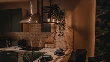 A modern kitchen with dark cabinets, a marble backsplash, and a hanging plant.