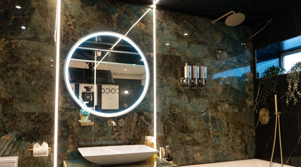 A modern bathroom with a large mirror, a white sink, and a shower area.