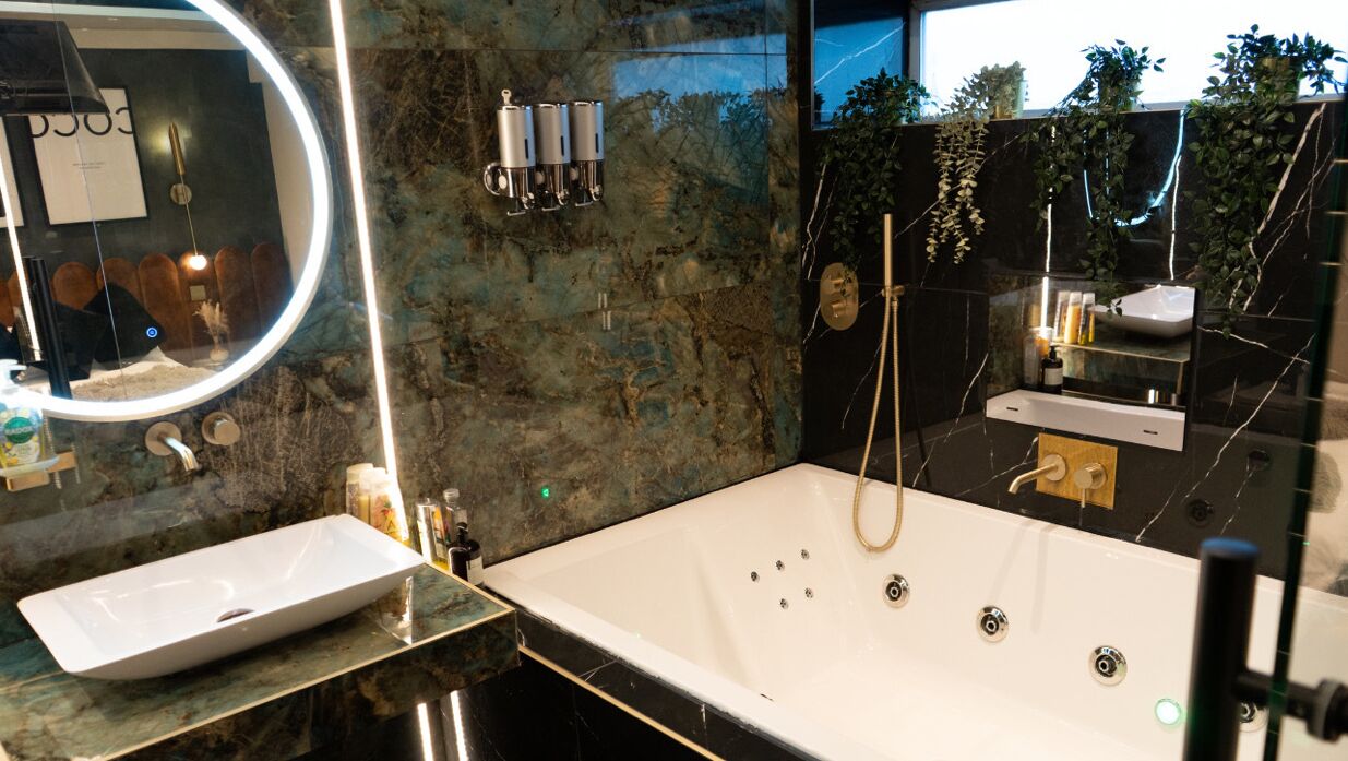 A modern bathroom with a large mirror, a white sink, a bathtub, and a shower area.