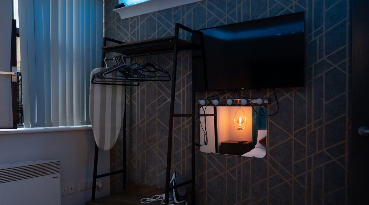 Een kamer met een ingebouwde grill, een kledingroede en een aan de muur bevestigde televisie.