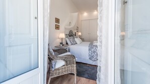Une chambre à coucher avec un lit, une chaise en osier, une table de chevet et une lampe.