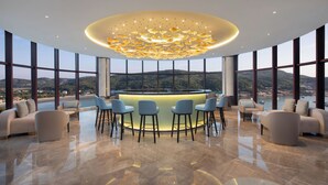 Un espace bar moderne doté d’un îlot central, de sièges et offrant une vue sur le paysage.