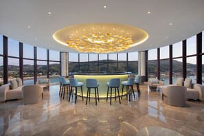 Un espace bar moderne doté d’un îlot central, de sièges et offrant une vue sur le paysage.